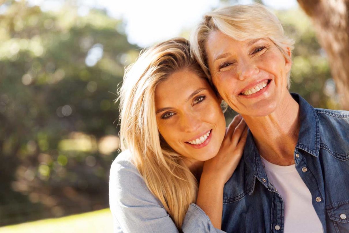 Two women smiling with a tooth denture