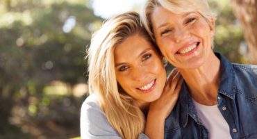 Two women smiling with a tooth denture